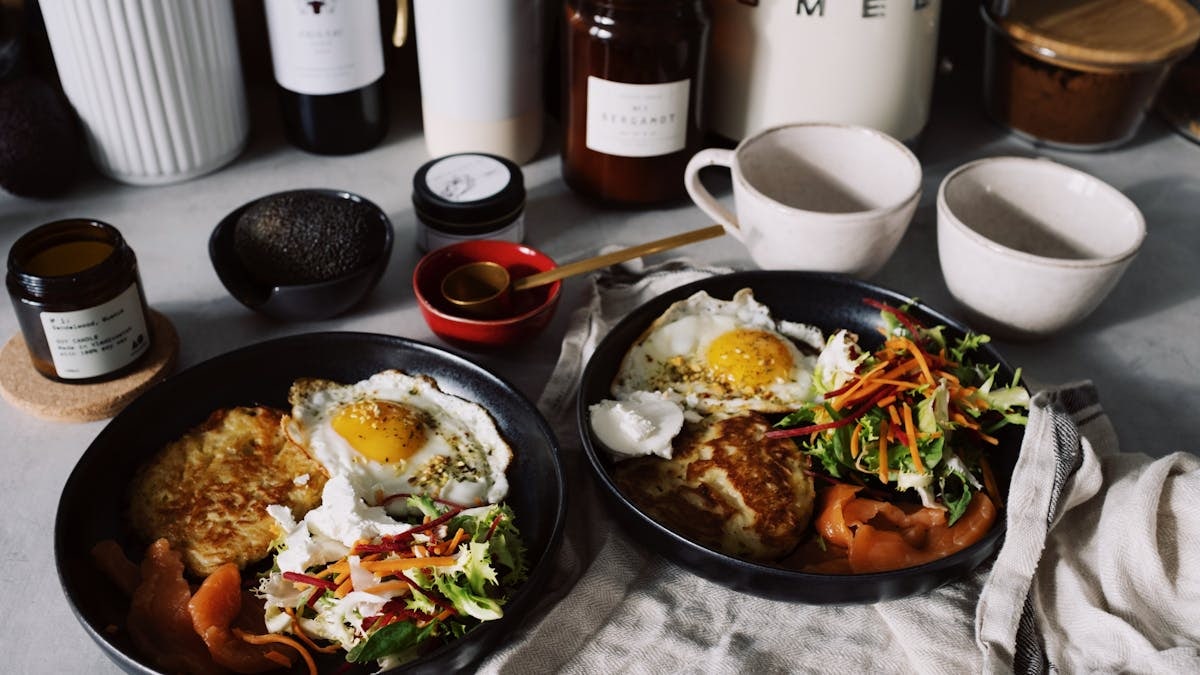 Tasty brunch spread with eggs, salad, and smoked salmon served on black plates.